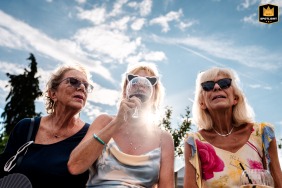 The mother of the bride and her friends enjoy cocktail hour together at Bergheim Pond in Alsace, France, beneath a bright sky